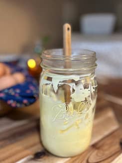 mayonnaise in a mason jar with a spatula on a wooden counter