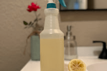 bottle of liquid on a bathroom sink with half of a lemon next to it