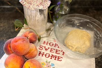 peaches and sourdough starter and pie crust in a bowl on the counter on a towel