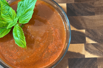 spaghetti sauce in a bowl with a sprig of basil