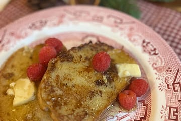 French Toast on a plate with syrup and raspberries