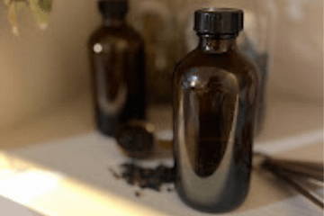 amber bottles on a shelf with jars in the background and dried elderberry in a tablespoon