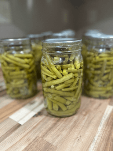 jars of canned green beans in rows on a wooden counter top