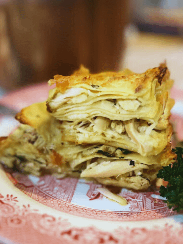 2 pieces of chicken alfredo lasagna on a plate with parsley on the side