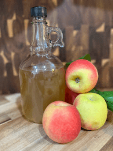 apple cider vinegar in a glass bottle with apples all around