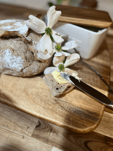Bread and butter on a wooden cutting board with white flowers